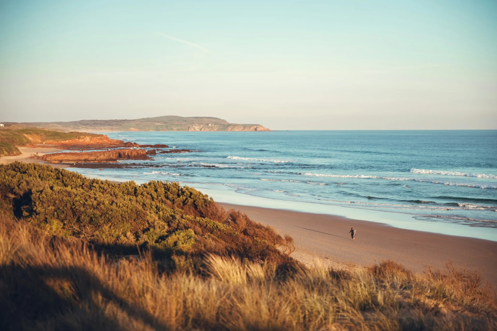 Golden hour on the Phillip Island coastline near Cowes — warm sandy beach, blue water, and coastal heathland